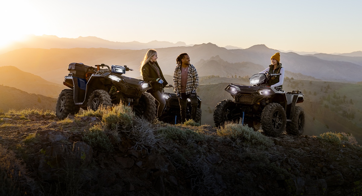 Polaris RZR side-by-side parked in front of a large stack of logs